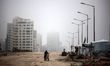A Palestinian man rides a bicycle along Rashid Street during the fog in Gaza City, on Marc...