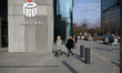 People walk past a PKO Bank Polski signage and logo in Warsaw, Poland, on March 21, 2025. 