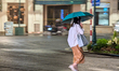 A woman holding an umbrella crosses the street near the intersection of Trang Tien and Ngu...
