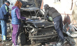 People stand by a damaged car in a residential area affected by a large-scale Russian dron...
