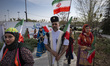 Iranian women and a man wear traditional dresses and carry Iranian flags before performing...