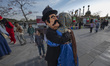 Two masked men play the roles of a traditional Iranian man and woman during a flag ceremon...
