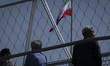 Afghan refugees in Iran stand under an Iranian flag on the Nature Bridge at a park during...