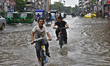 Vehicles try driving and Citizens waking through the flooded streets of Dhaka after heavy...