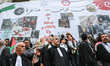 Tunisian lawyers wear the legal gown and stand in front of a giant banner that reads in Ar...