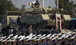 An Iranian military personnel is carried by a military tank during a military parade comme...
