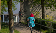 A woman with bright pink hair walks along a pedestrian path while a man stands nearby a gr...