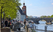 Crowds of people walk and relax along the tree-lined Danube promenade near the historic St...
