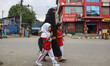 A Kashmiri Muslim woman and school children walk past Indian paramilitary soldiers guardin...
