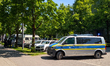 A German police van with flashing blue lights parks on a residential street as officers ch...