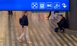 Passengers walk through the concourse under a blue directional sign at Prague Central Stat...