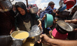 Palestinians line up to receive a hot meal at a food distribution point in the Al-Rimal ne...