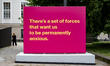 A billboard reads 'There's a set of forces that wants us to be permanently anxious' in the...