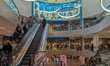 People use escalators and browse multiple levels of the PEP shopping center in front of th...