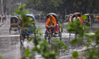 People and vehicles move on the street during a heavy rainfall in Dhaka, Bangladesh, on Ma...
