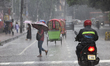 People and vehicles move on the street during a heavy rainfall in Dhaka, Bangladesh, on Ma...