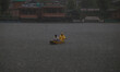 A man rows a boat on the waters of Dal Lake during heavy rainfall in Srinagar, Jammu and K...