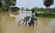 A man pushes his bicycle through a flooded street after heavy rains in Kampur, Nagaon Dist...