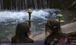 Two young Iranian women sit next to hookahs at an outdoor restaurant in the Darband neighb...