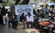 People sit in front of a loan advertisement board in Mumbai, India, on June 6, 2025. In a...