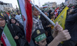 A young boy wearing a military uniform holds an Iranian flag during a religious rally call...