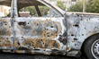 Shrapnel holes dot a calcined car that catches fire as a result of a Russian drone attack...