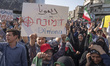 An Iranian protester holds up an anti-Israeli placard as other protesters shout anti-U.S....