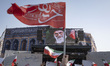 Iranian protesters wave flags under a portrait of Iran's Supreme Leader, Ayatollah Ali Kha...