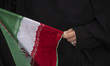 A veiled Iranian woman holds a country flag during a protest to condemn the U.S. attacks o...