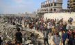 People carrying aid packages walk along Al-Rashid Street in western Jabalia on June 22, 20...