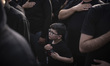 A young Iranian boy beats himself as he and his father participate in a mass mourning cere...