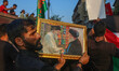 A Kashmiri Shiite Muslim mourner holds a photo frame displaying portraits of slain Lebanes...
