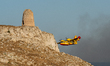 A Canadair aircraft passes Torre del Serpe during a wildfire emergency near Baia delle Ort...