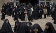 Veiled Iranian women walk out of a prayer hall after participating in a ceremony to mark t...