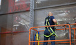 Workers use a high-pressure water spray and other equipment for hours to remove red spray...