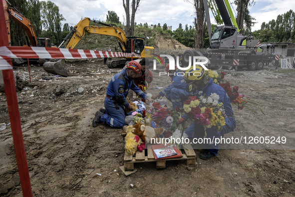 On August 1, 2025, in Kyiv, Ukraine, rescuers place flowers and toys in memory of the residents killed when a Russian missile strikes a mult...