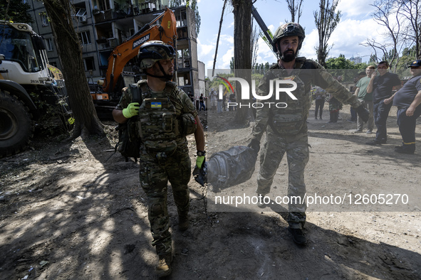 In Kyiv, Ukraine, on August 1, 2025, explosive ordnance experts carry a part of the cruise missile that strikes a multi-storey residential b...