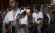 A young Iranian street musician plays the guitar on a sidewalk in a shopping and dining ar...