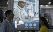 Attendees walk past a large display promoting an Epson SCARA robot at the Automation Expo...