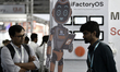 Attendees look at a display featuring a robot mascot at the Robotspace booth during the Au...