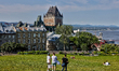 People picnic along the Plains of Abraham with the Fairmont Le Chateau Frontenac visible i...