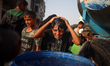 A Palestinian young man rinses his head with water amidst soaring temperatures in western...