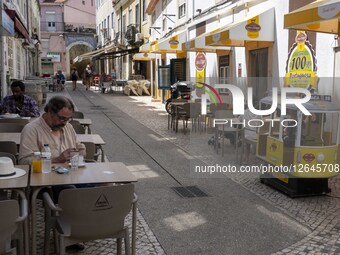 A person sits on the terrace of a restaurant near a toy tram in the Graca district of Lisbon, Portugal, on August 6, 2025. Portugal faces a... by Jorge Mantilla/NurPhoto