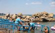 Workers help a man in a wheelchair get into the Black Sea at Bezmezh Accessible Beach in O...