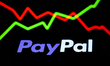 An illustrative stock graph displayed on a screen and PayPal logo displayed on a phone scr...