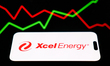An illustrative stock graph displayed on a screen and Xcel Energy logo displayed on a phon...