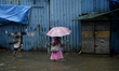 People wade through a flooded street with umbrellas during heavy monsoon rains in Mumbai,...