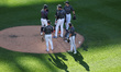 New York Mets players gather at the pitcher's mound during a pitching change in the third...