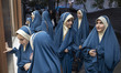 Veiled young Iranian women stand together on a sidewalk during a religious rally commemora...