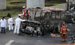 Experts analyze a burned truck due to the explosion of a gas tanker that overturns near th...